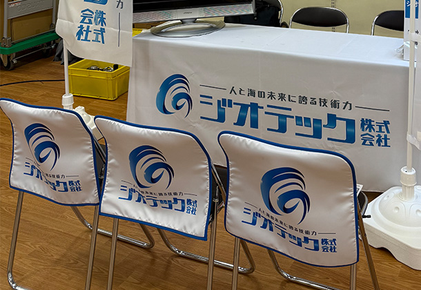 実績事例1677:水中工事業者様のイベント用オリジナル椅子カバー、テーブルクロス、のぼり 活用風景